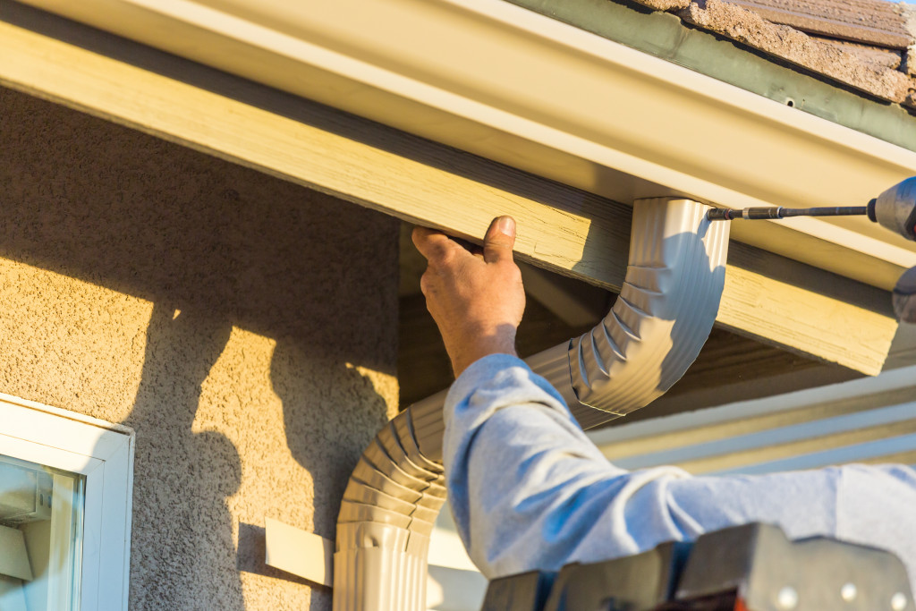 Man fixing rain gutter before rainy season