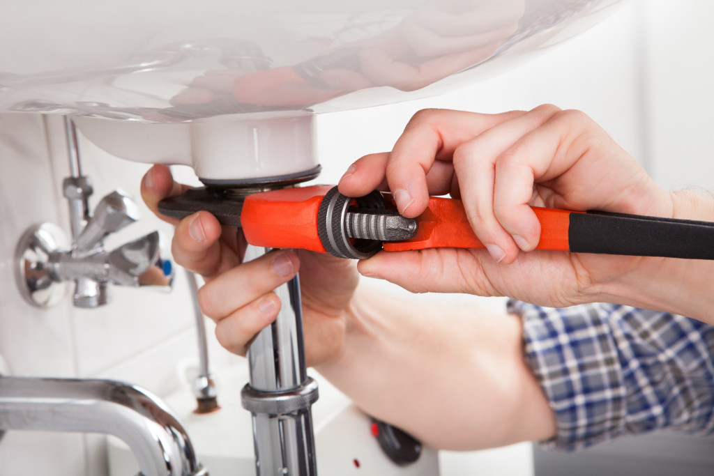 A man fixing the sink in the bathroom