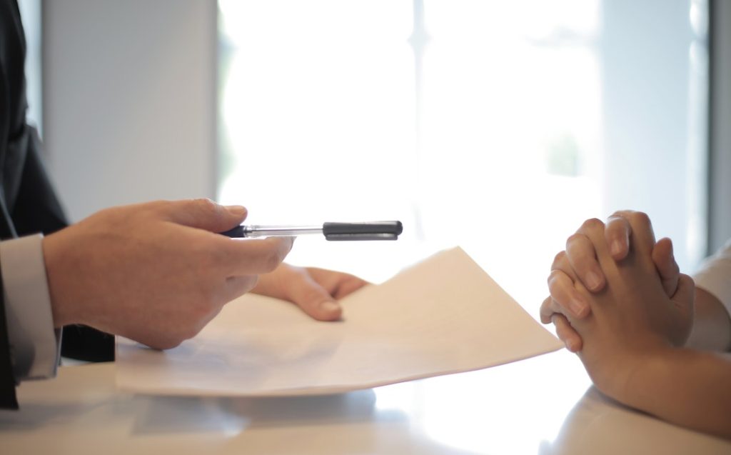 Crop businessman giving contract to woman to sign