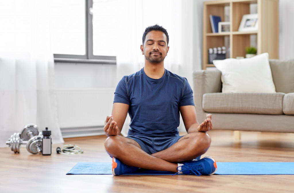 A man meditating on a yoga mat at home