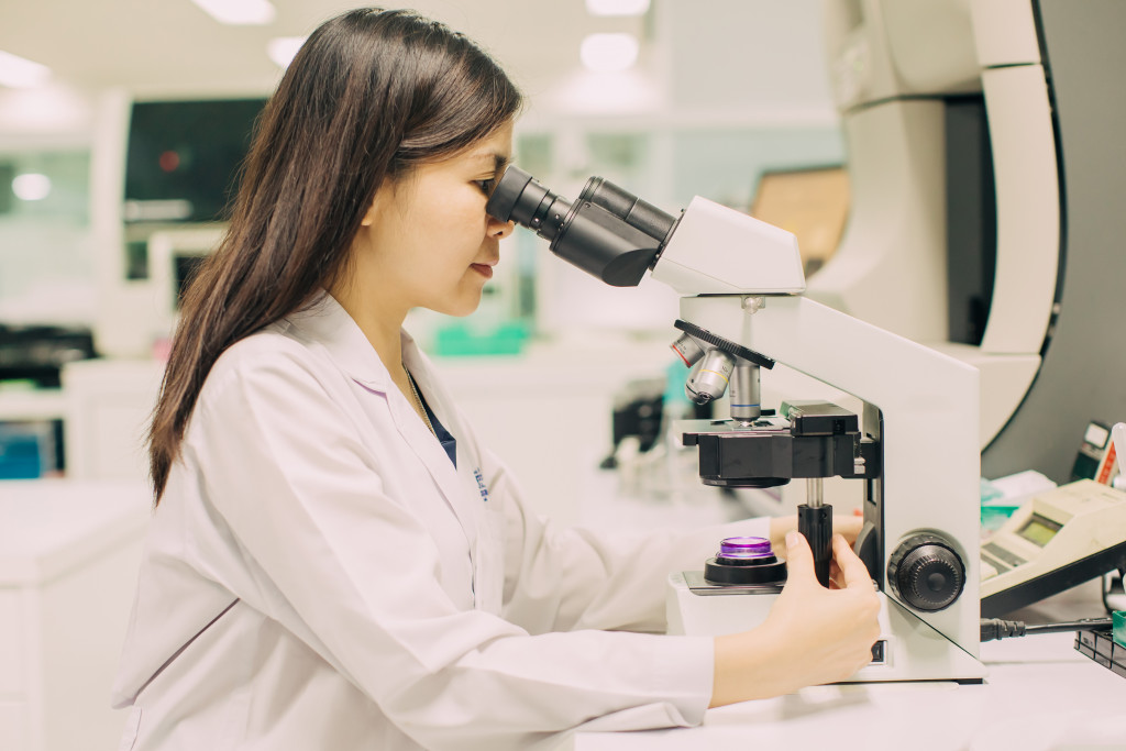 A woman looking through a microscope for research